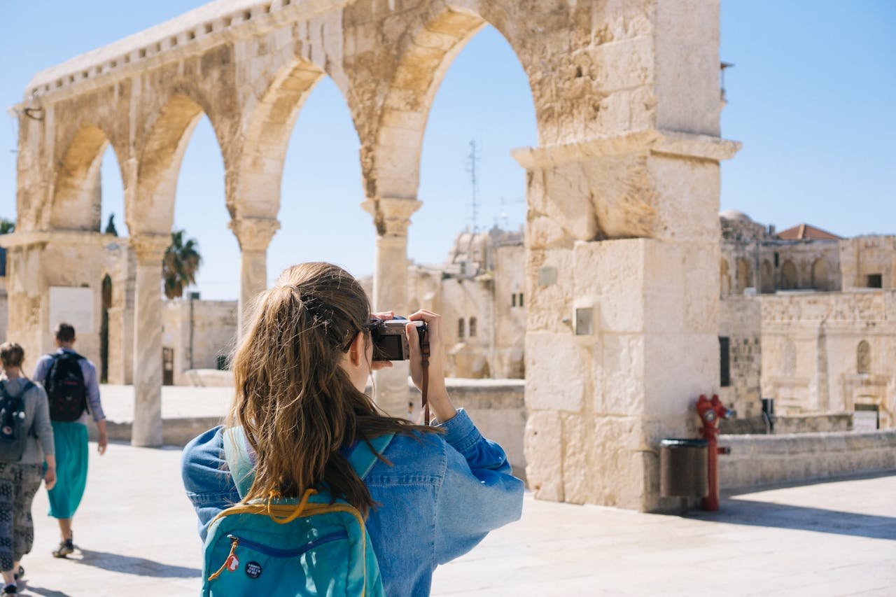 vision A tourist photographs the ancient stone arches in Jerusalem's Old Town, capturing the essence of travel and history.
