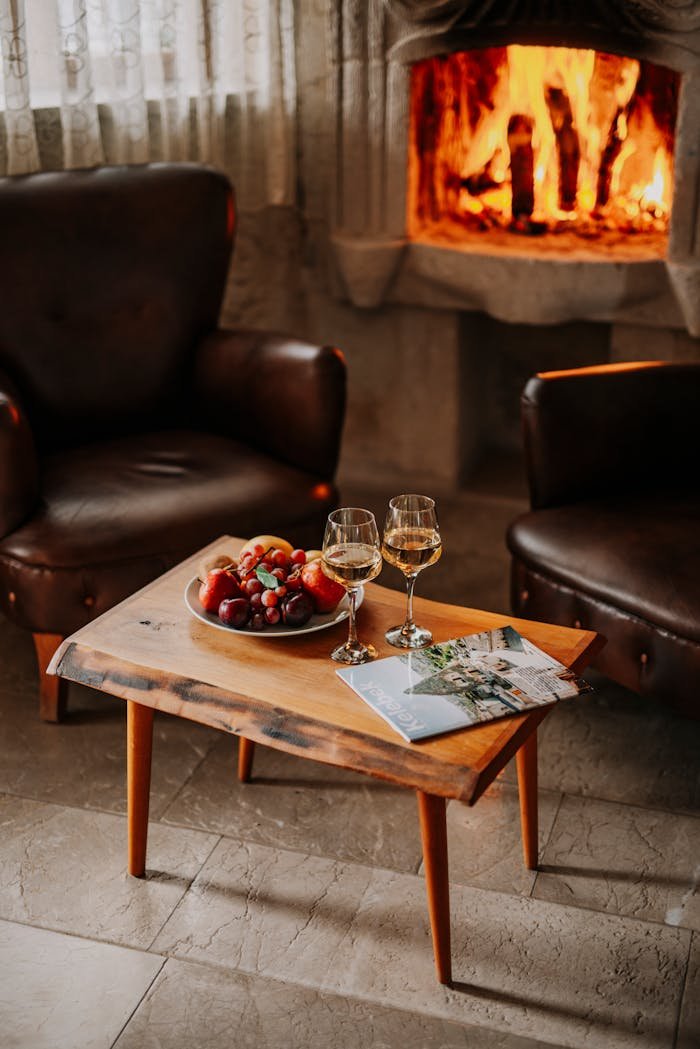 Warm indoor setting with wine and fruit near a fireplace, perfect for a cozy evening.