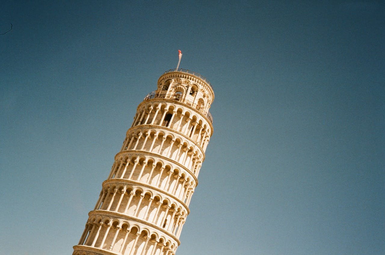 The Art of Drawing Readers In: Your attractive post title goes here Iconic low angle view of the Leaning Tower of Pisa with a clear blue sky overhead, emphasizing its architectural beauty.